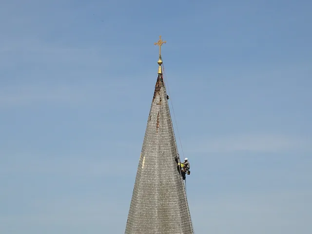 Szakember kötélbiztosítással a templomtorony fedélszerkezetét újítja fel